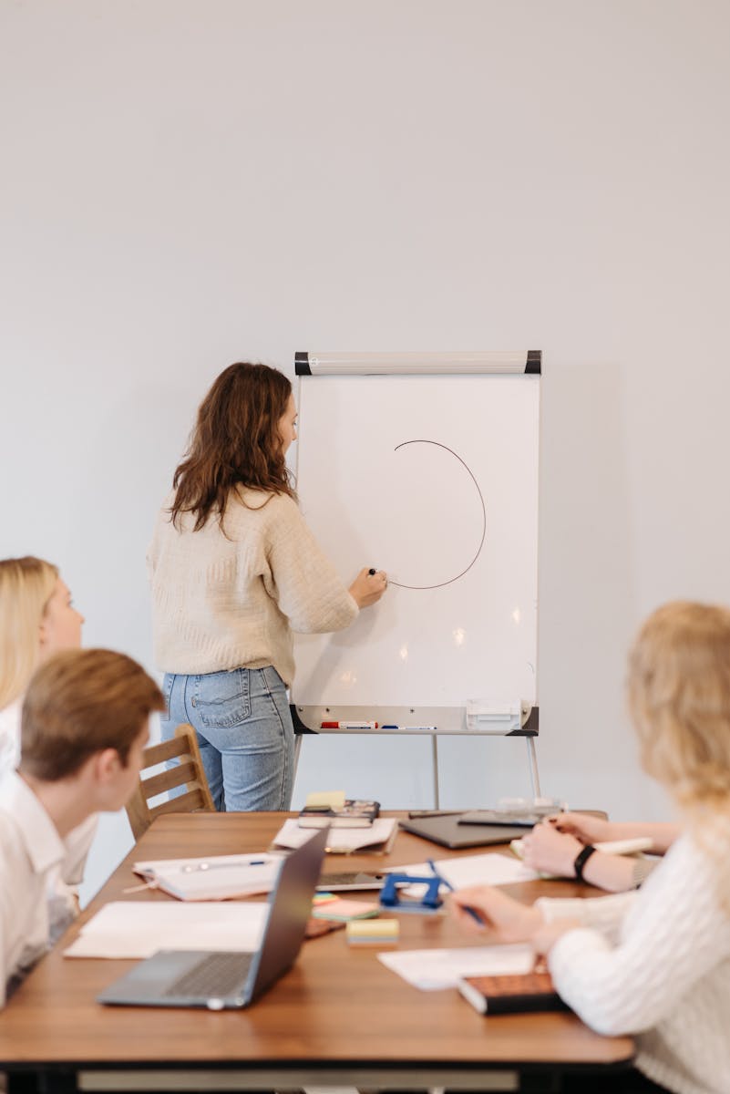 A woman leads a brainstorming session at an office meeting with a team around a table.